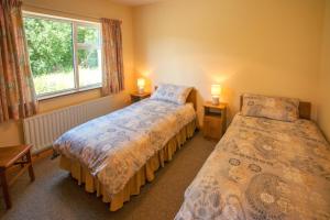 two beds in a room with a window and two lamps at Cottage 390 - Maam in Claggan