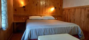 um quarto com uma cama com lençóis brancos e paredes de madeira em Cabañas Turin em Puerto Puyuhuapi