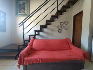 um sofá vermelho numa sala de estar com uma escada em Village Funchal 03, Lençóis em Lençóis