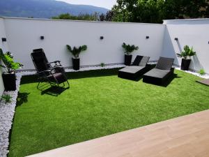 une arrière-cour avec de l'herbe, des chaises et un mur blanc dans l'établissement Istočno Sarajevo, à Sarajevo