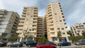 dos edificios altos con autos estacionados en un estacionamiento en Adriatik Apartment, en Durrës