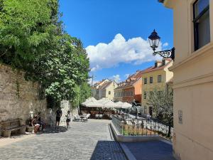 a cobblestone street with people sitting on benches and buildings at Apartment Azalea in Zagreb