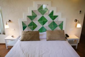 a bedroom with a white bed with a geometric headboard at Casale La Macina - Hotel, Scopello in Scopello