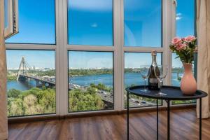 キーウにあるApartments with crazy panoramic view of the Dnieprの花瓶とワイングラス2杯付きのテーブルが備わる客室です。