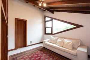 ein Wohnzimmer mit einem Sofa und einem Fenster in der Unterkunft 4 Suítes + Piscina e Área Gourmet | 3 Irmãos in Búzios