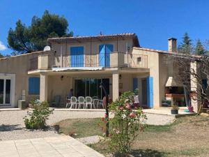Saint-DidierにあるMaison d'Hôtes & Spa La Chêneraie-Provence Ventouxの大きな家で、バルコニー(椅子付)が備わります。