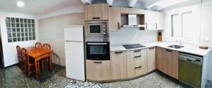a kitchen with a table and a white refrigerator at Cal PAU DE LA GRALLA in Pobla de Montornés