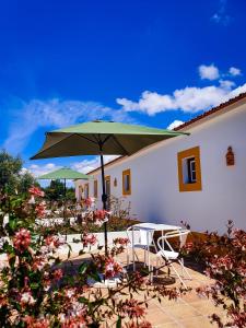 um pátio com uma mesa, cadeiras e um guarda-sol em Monte do Brejinho de Água no Carvalhal