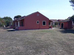 a red and pink house with a yard at Aggeliki Apartments in Sidari