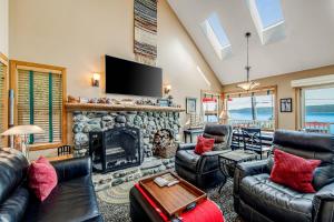 sala de estar con muebles de cuero y chimenea de piedra. en Tyee Legacy, en Tyee Beach