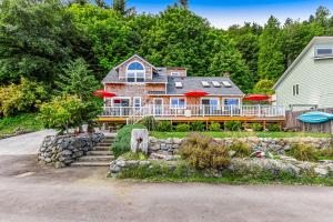 ein großes Haus mit einer großen Terrasse mit roten Sonnenschirmen in der Unterkunft Tyee Legacy in Tyee Beach