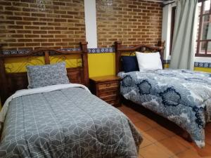 a bedroom with two beds and a brick wall at Hotel Y Suites Axolotl in Chignahuapan