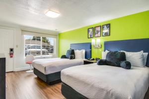 a hotel room with two beds and a green wall at Signature Inn Eugene in Eugene