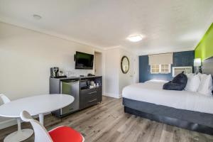 a hotel room with a bed and a desk and a table at Signature Inn Eugene in Eugene