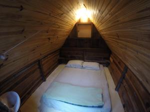 a small bed in a wooden room with a light at Gran Camping Cabanas da Fazenda in Visconde De Maua