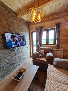 - un salon avec un canapé et une télévision sur un mur en briques dans l'établissement Original Wooden Lodge 2, à Žabljak