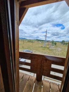 une fenêtre donnant sur un champ depuis une terrasse couverte dans l'établissement Original Wooden Lodge 2, à Žabljak