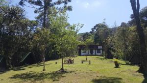 a house in the middle of a field with trees at Gran Camping Cabanas da Fazenda in Visconde De Maua