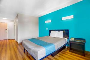 a room with a bed with a blue wall at Motel 6-Raleigh, NC - North in Raleigh