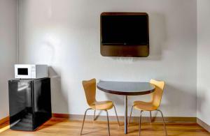 a table and two chairs and a tv on a wall at Motel 6-Raleigh, NC - North in Raleigh
