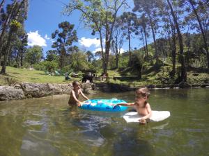 dos niños jugando en el agua en un río en Gran Camping Cabanas da Fazenda en Visconde De Maua