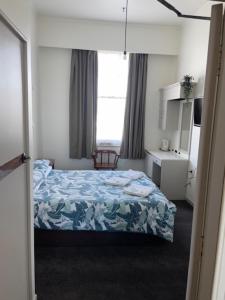 una piccola camera con letto e finestra di Grand Hotel - Whangarei a Whangarei