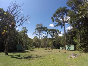 a park with people sitting in a grass field at Gran Camping Cabanas da Fazenda in Visconde De Maua