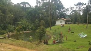 a group of people standing around a pond in a field at Gran Camping Cabanas da Fazenda in Visconde De Maua