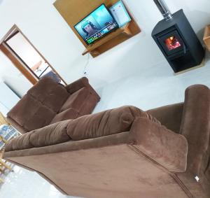 un sofá marrón en la sala de estar con TV en Cantinho do Sossego III - Com Lareira, en Canela