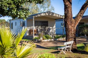 a blue house with a tree and a white bench at Gardenview in Wangaratta