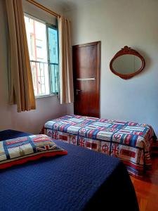 a room with two beds and a mirror and a window at Apartamento Copacabana Mar in Rio de Janeiro