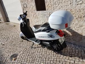 una moto blanca estacionada en una calle de ladrillos en Room Lusíadas with private bathroom, en Lisboa