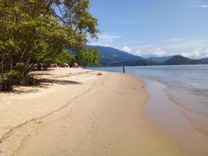 a person walking on a beach near the water at Casa na praia do Jabaquara in Paraty