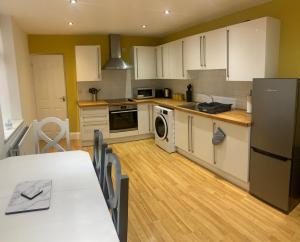 una cocina con armarios blancos y una mesa. en Gateshead Serviced Apartment Ideal for Contractors and Vacationing, en Gateshead