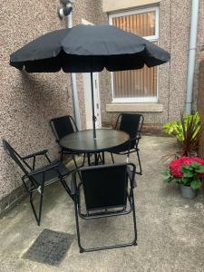 una mesa y sillas bajo una sombrilla negra en Gateshead Serviced Apartment Ideal for Contractors and Vacationing, en Gateshead