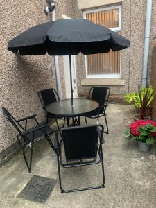 a table and chairs under a black umbrella at Gateshead Serviced Apartment Ideal for Contractors and Vacationing in Gateshead