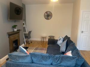 a living room with a blue couch and a fireplace at Gateshead Serviced Apartment Ideal for Contractors and Vacationing in Gateshead