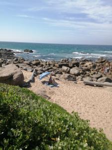 a person sitting on a beach with an umbrella at 12 Uvongo Breeze in Uvongo Beach