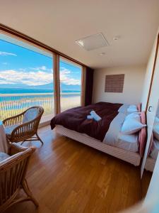 ein Schlafzimmer mit einem Bett und einem großen Fenster in der Unterkunft ゲストハウスジャパン西伊豆/The Guest House Japan Nishi-Izu in Toda
