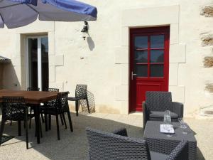 eine Terrasse mit einem Tisch, Stühlen und einer roten Tür in der Unterkunft Gîte Dommartin-le-Franc, 3 pièces, 4 personnes - FR-1-611-64 