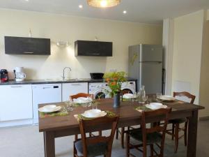 a kitchen with a wooden table with chairs and a kitchen with a refrigerator at Gîte Dommartin-le-Franc, 4 pièces, 6 personnes - FR-1-611-63 