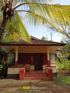 a small house with a porch and a palm tree at Cherai Beach Resorts in Cherai Beach