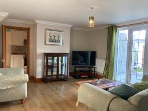 a living room with a couch and a tv at Bader House in Aberporth