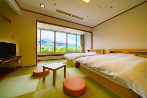 een slaapkamer met 2 bedden en een groot raam bij Hotel Beppu Pastoral in Beppu