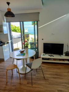 Una sala de estar con una mesa y sillas y un televisor. en Refúgio de Pedra, en Fajã da Ovelha