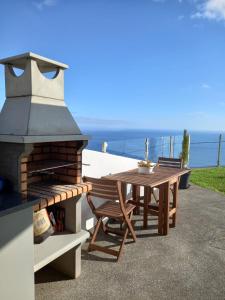 a patio with a table and a pizza oven at Refúgio de Pedra in Fajã da Ovelha