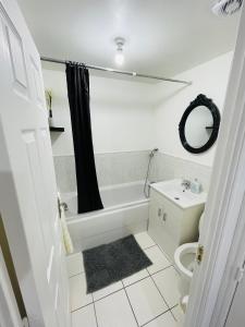 ein Badezimmer mit einer Badewanne, einem WC und einem Waschbecken in der Unterkunft Watan Cottage - Spacious 3 Bedrooms Entire House With Beautiful Outdoor Garden in Manchester