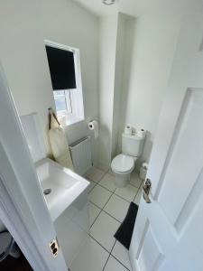 a white bathroom with a toilet and a sink at Watan Cottage - Spacious 3 Bedrooms Entire House With Beautiful Outdoor Garden in Manchester