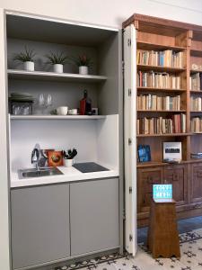 een keuken met een wastafel en een boekenplank bij Sognalibro Bed and Books in Ragusa