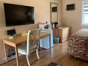 a room with a desk and a bed and a television at Green View Motel and RV Park in Greenwood